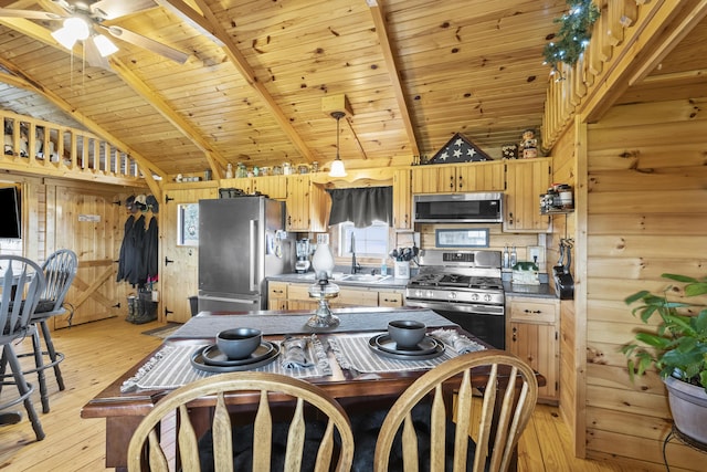 kitchen with stainless steel appliances, wood walls, a sink, and light wood-style floors