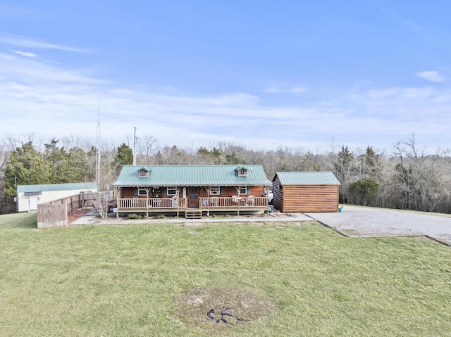 back of house with metal roof, a yard, an outdoor structure, and a wooden deck