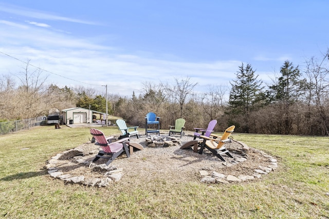 view of yard featuring an outdoor fire pit, a detached garage, fence, and an outdoor structure