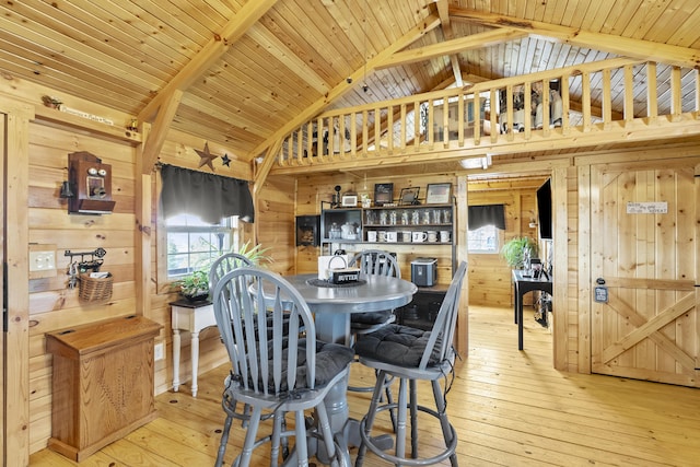 dining area featuring wooden walls, wooden ceiling, light wood-type flooring, high vaulted ceiling, and beam ceiling