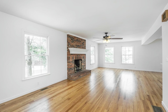 unfurnished living room with light wood-type flooring, baseboards, a fireplace, and visible vents