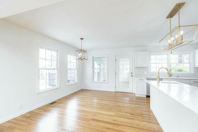 unfurnished dining area featuring visible vents, light wood-style floors, a sink, a chandelier, and baseboards