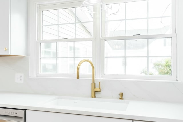 room details featuring light countertops, white cabinetry, a sink, and stainless steel dishwasher