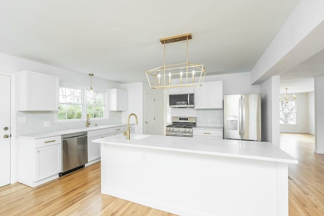 kitchen featuring an inviting chandelier, stainless steel appliances, light countertops, a large island with sink, and a sink