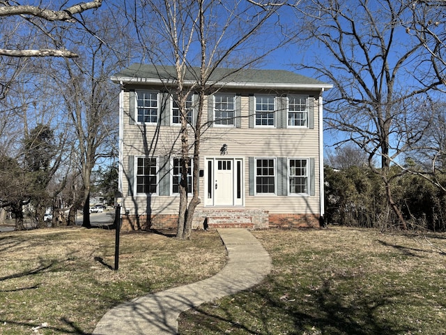 colonial-style house featuring a front lawn