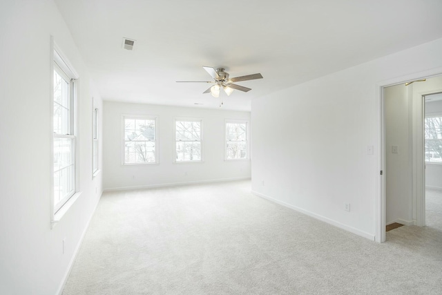 spare room featuring light carpet, baseboards, visible vents, and ceiling fan