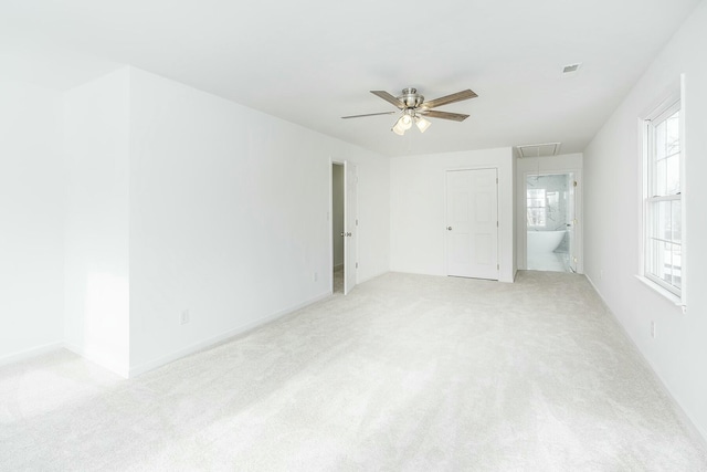 empty room featuring light carpet, ceiling fan, visible vents, and attic access