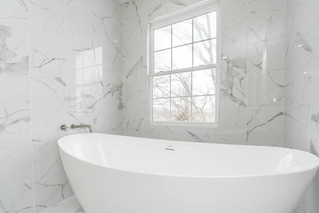 full bathroom featuring stone wall and a soaking tub