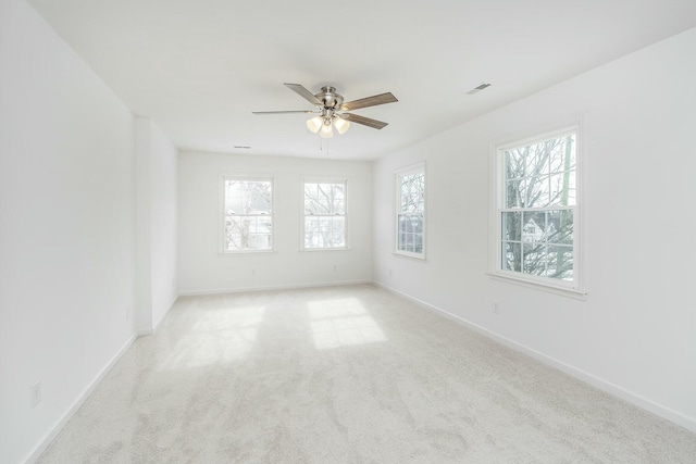 spare room featuring visible vents, baseboards, a ceiling fan, and light colored carpet