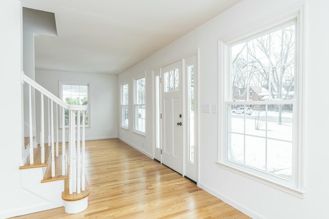 foyer featuring stairs, light wood-type flooring, and baseboards