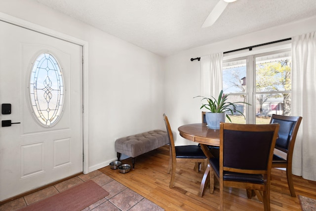 dining room featuring light wood-style flooring, a textured ceiling, and baseboards