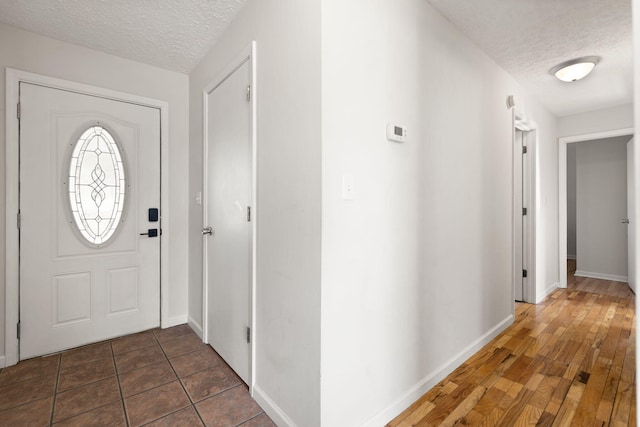 foyer featuring a textured ceiling, baseboards, and wood finished floors