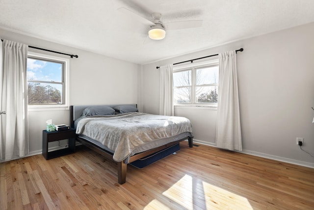 bedroom with baseboards, multiple windows, and light wood-style floors