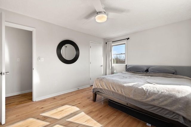 bedroom with a ceiling fan, light wood-style flooring, and baseboards