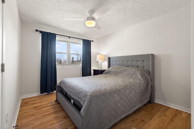 bedroom featuring a textured ceiling, baseboards, and wood finished floors