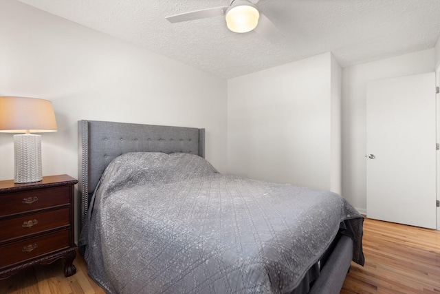 bedroom featuring a textured ceiling, a ceiling fan, and wood finished floors