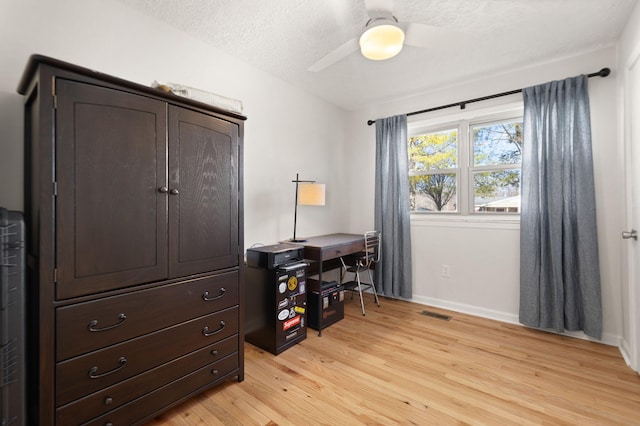 office space featuring visible vents, baseboards, a ceiling fan, a textured ceiling, and light wood-style floors