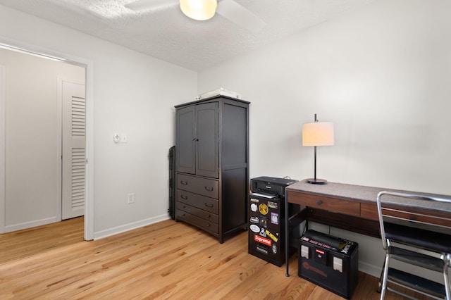 office space with ceiling fan, a textured ceiling, light wood-type flooring, and baseboards