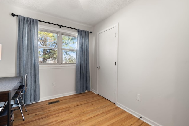 office featuring light wood finished floors, baseboards, visible vents, and a textured ceiling