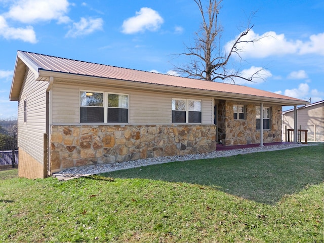 view of front of home with stone siding, metal roof, and a front lawn