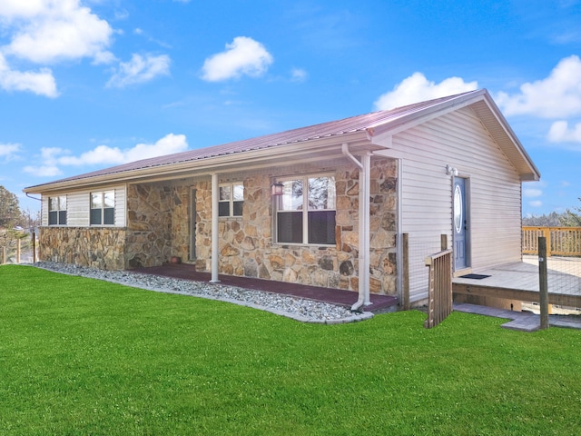 rear view of property with stone siding, a lawn, and metal roof