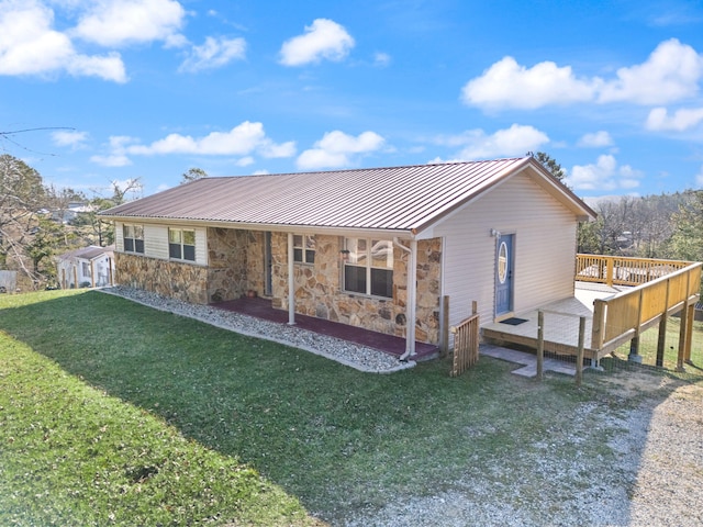 rear view of house featuring a deck, metal roof, stone siding, a lawn, and a standing seam roof