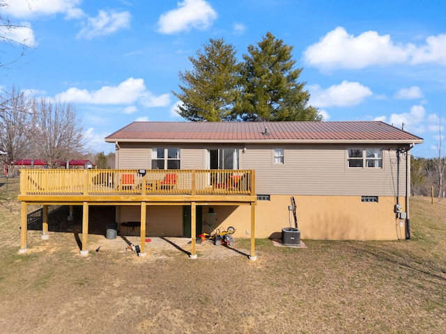 rear view of house featuring metal roof, a lawn, and a wooden deck