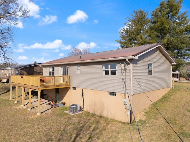 back of property with cooling unit, metal roof, a yard, and a deck