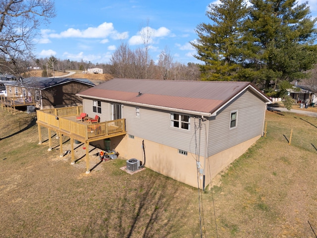 back of property with metal roof, a lawn, a deck, and central AC unit