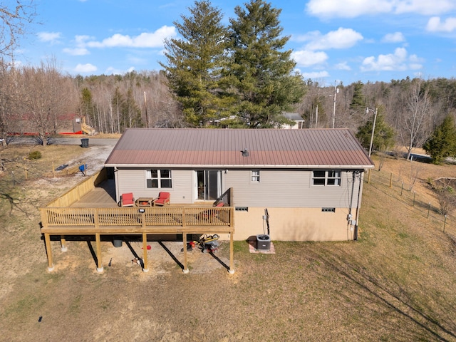 rear view of house with a forest view, a yard, metal roof, and a wooden deck