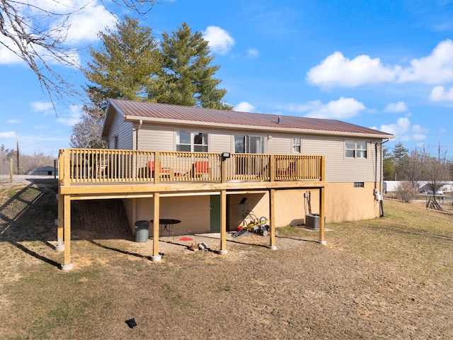 rear view of property with a deck, metal roof, and a lawn