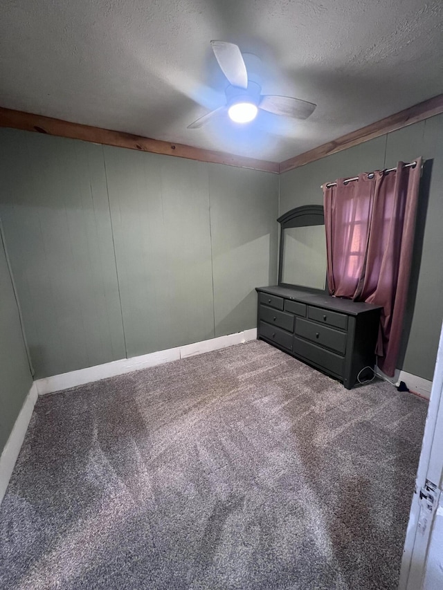 unfurnished bedroom with a textured ceiling, ceiling fan, carpet flooring, and baseboards