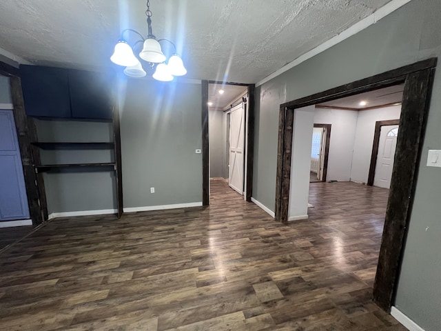 empty room with dark wood-style flooring, a textured ceiling, baseboards, and an inviting chandelier