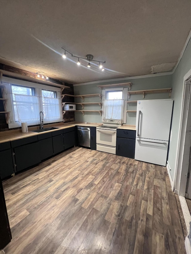 kitchen with open shelves, light wood-style floors, a sink, white appliances, and dark cabinetry