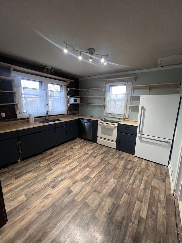 kitchen featuring wood finished floors, white appliances, a sink, and open shelves