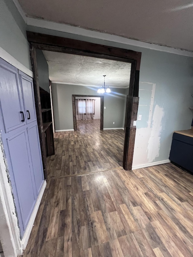 corridor with baseboards, a chandelier, dark wood finished floors, and a textured ceiling