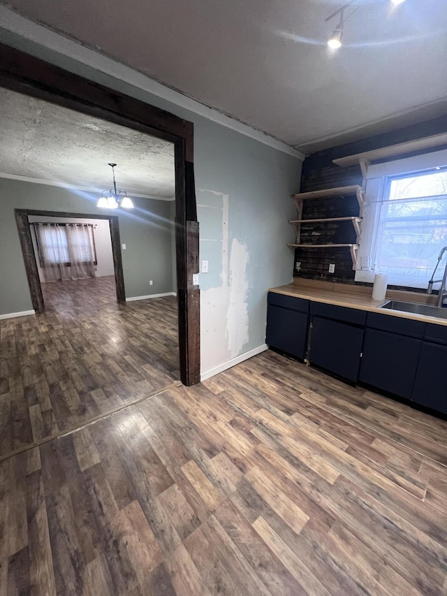 kitchen with light countertops, a sink, a textured ceiling, wood finished floors, and a chandelier