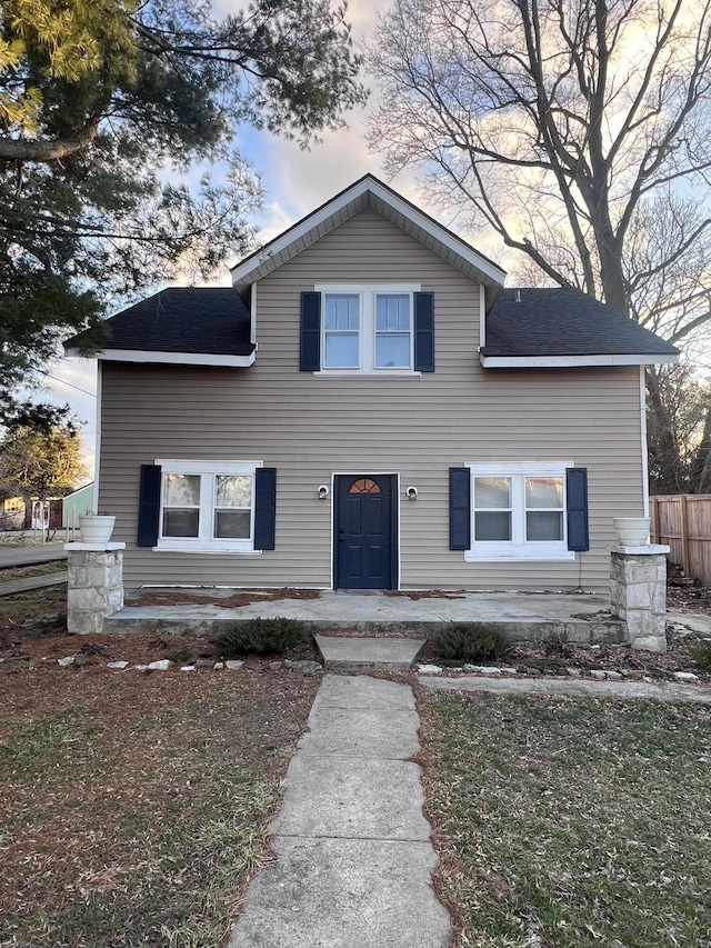 traditional home with a shingled roof and fence