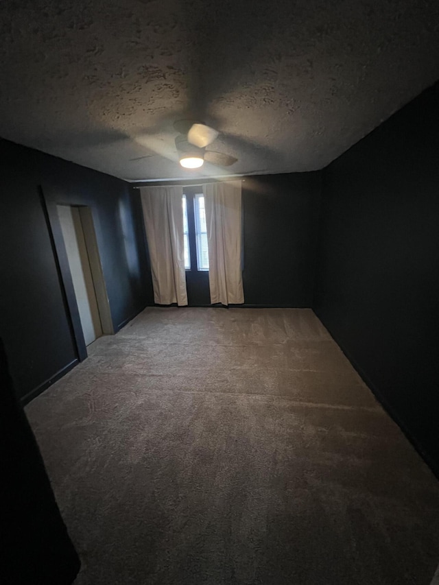 spare room with ceiling fan, a textured ceiling, and light colored carpet