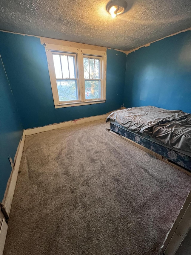 unfurnished bedroom with carpet, a textured ceiling, and baseboards