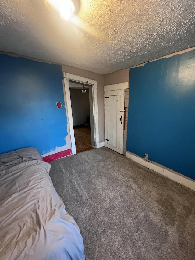 bedroom featuring a textured ceiling, carpet, and baseboards