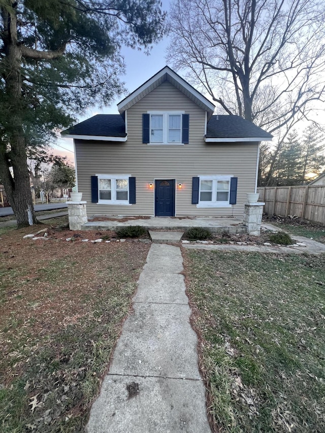 view of front facade with a shingled roof and fence