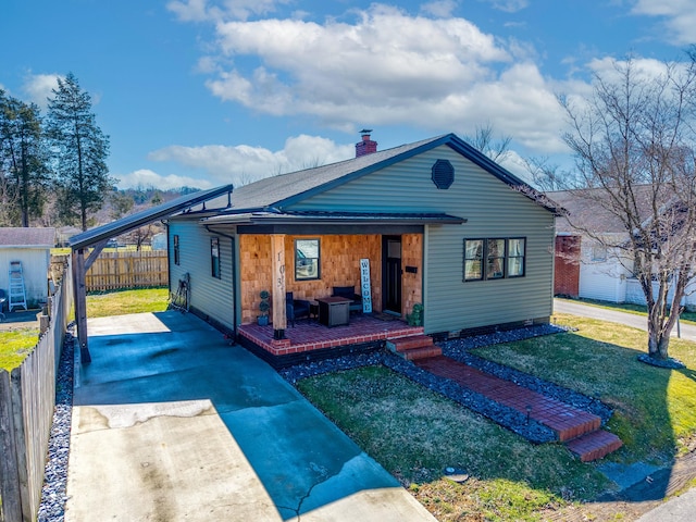 rear view of property featuring a chimney, a yard, driveway, and fence