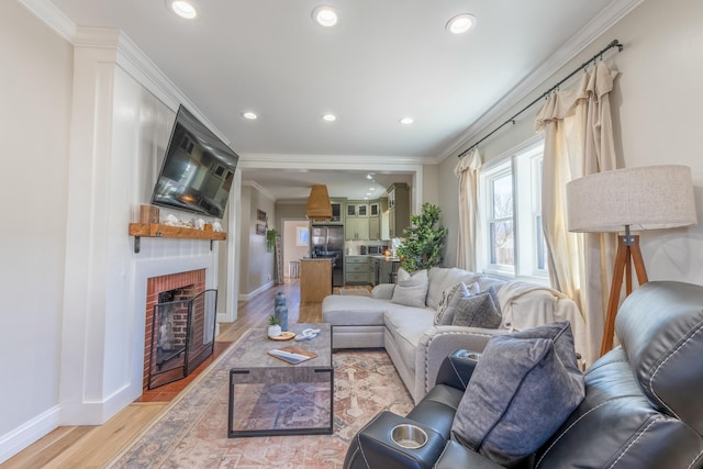 living area with recessed lighting, a fireplace, light wood-style flooring, and crown molding