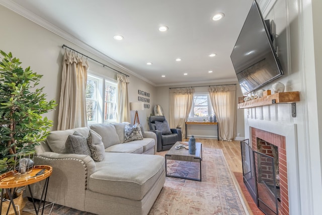 living room featuring a brick fireplace, light wood-style flooring, crown molding, and recessed lighting