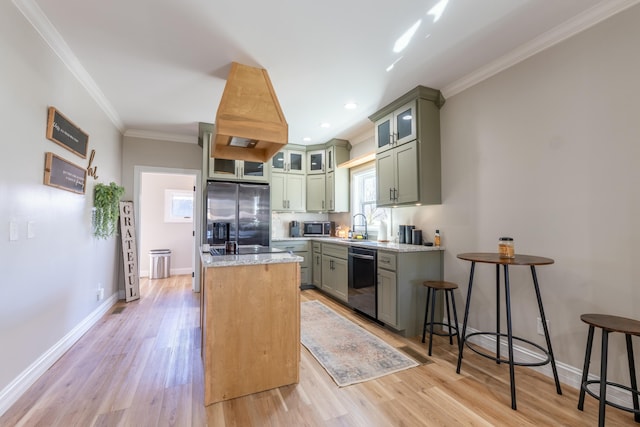 kitchen with a kitchen island, ornamental molding, light stone countertops, stainless steel appliances, and light wood-type flooring