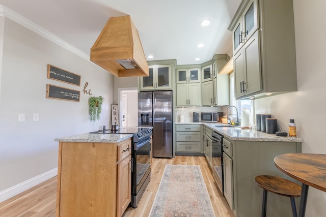 kitchen with a kitchen island, light stone counters, custom exhaust hood, stainless steel appliances, and a sink