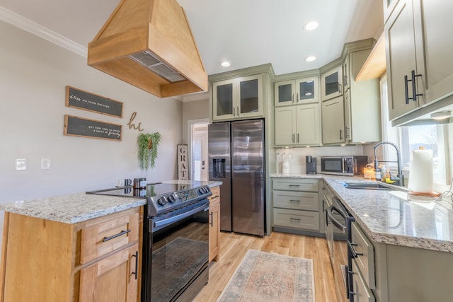 kitchen featuring light wood finished floors, custom exhaust hood, appliances with stainless steel finishes, a sink, and light stone countertops