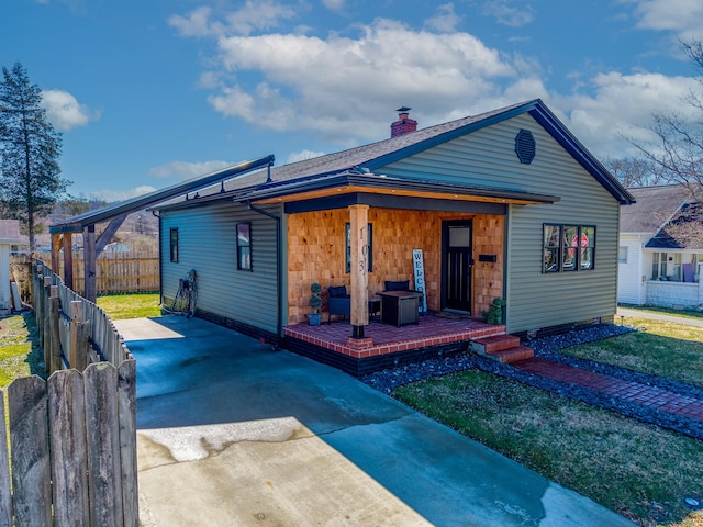 bungalow-style house featuring driveway, a chimney, fence, and a front yard