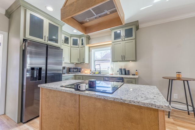 kitchen with appliances with stainless steel finishes, light stone counters, crown molding, light wood-type flooring, and a sink